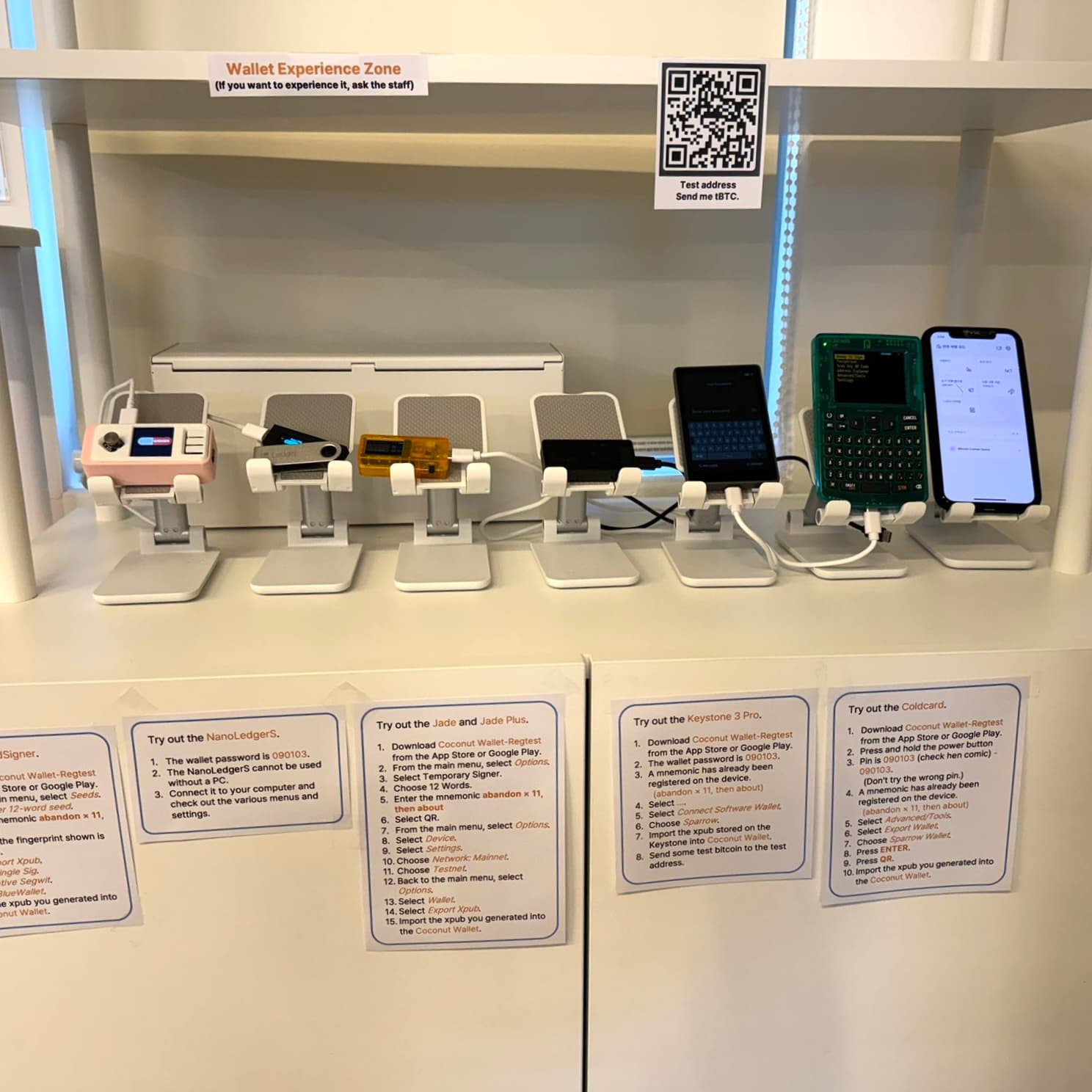 Several hardware wallets and a phone displayed on white stands