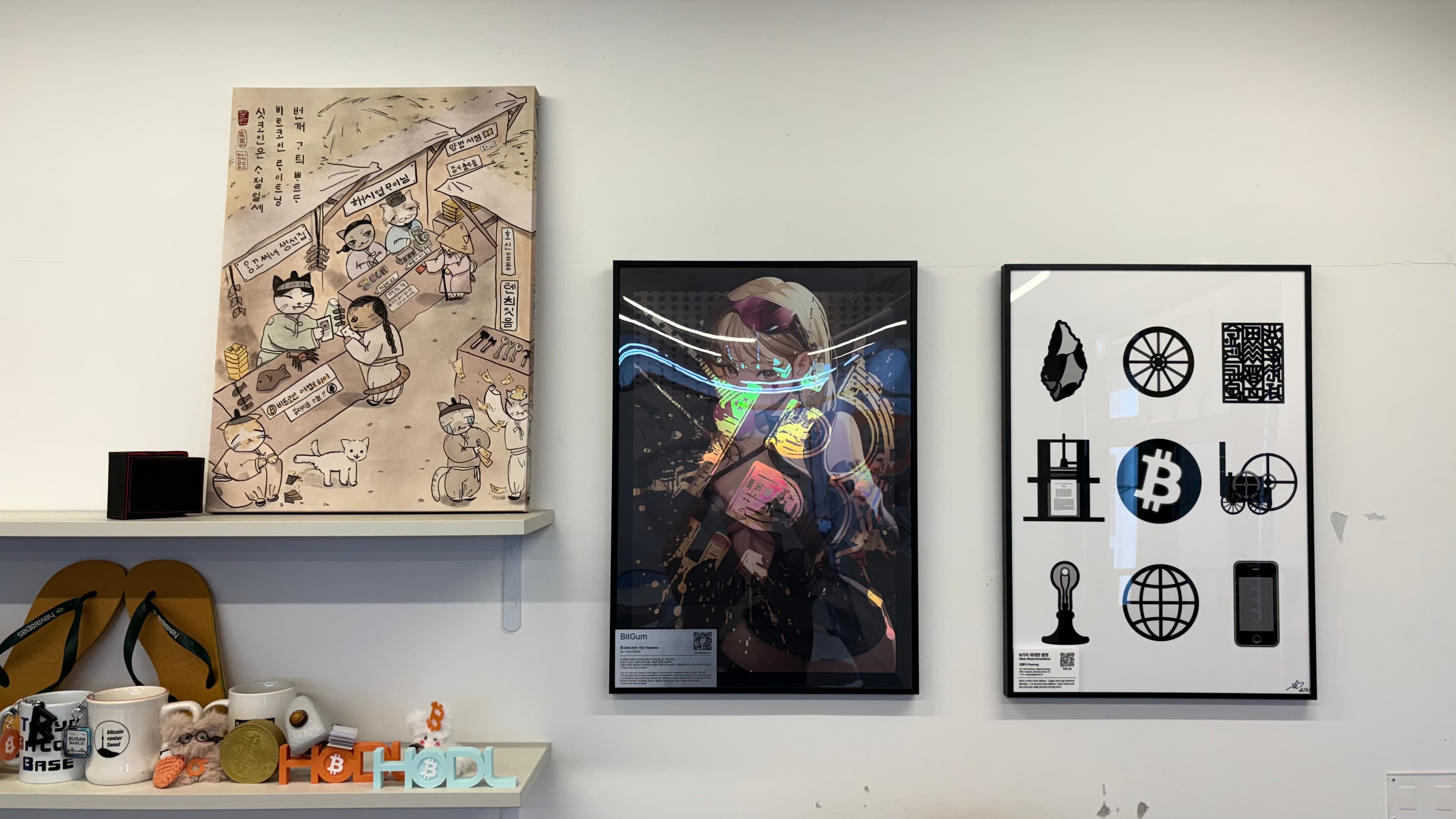 Three Bitcoin-related illustrations and prints on a wall at the center