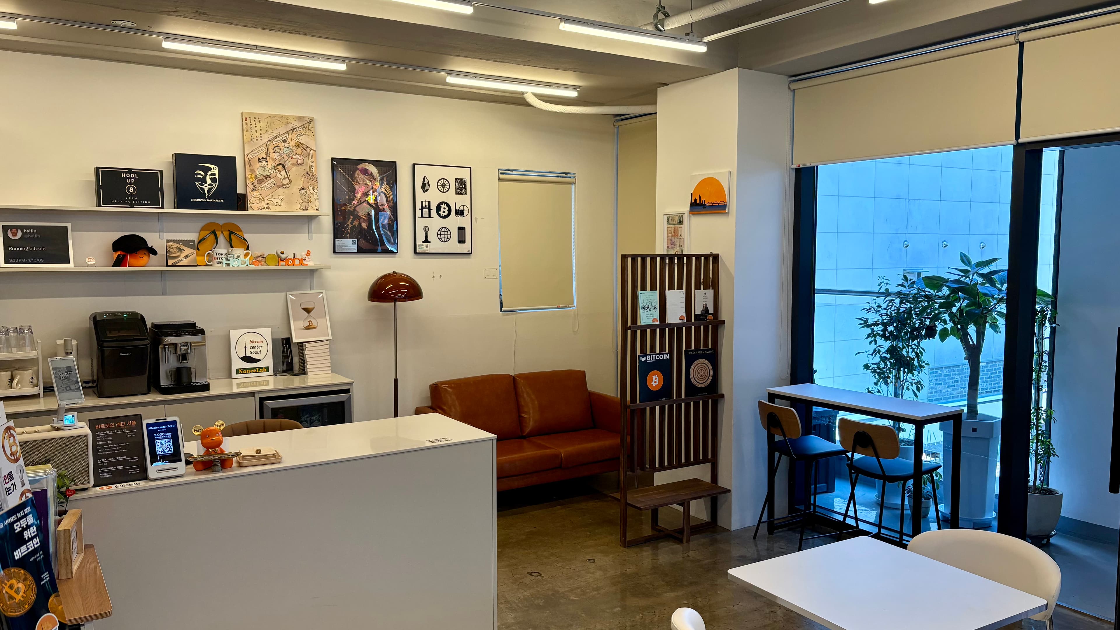 Center lounge with Bitcoin books and art, a brown sofa and window seating